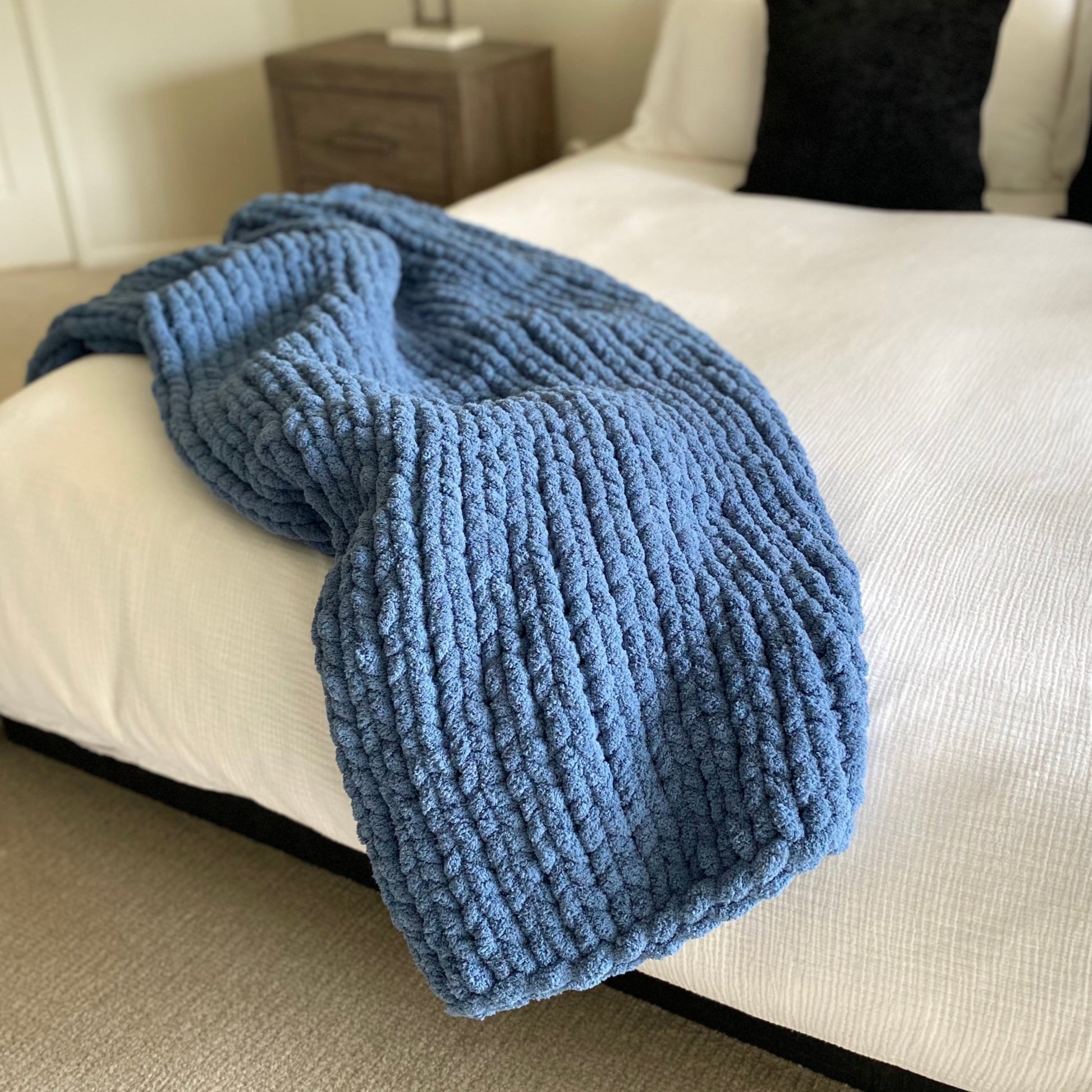 Medium chunky knit blanket in Cold Sea draped over a king bed.