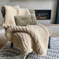 Small chunky knit blanket in Taupe draped over a chair.