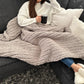 Small chunky knit blanket in Grey draped over a woman's lap.